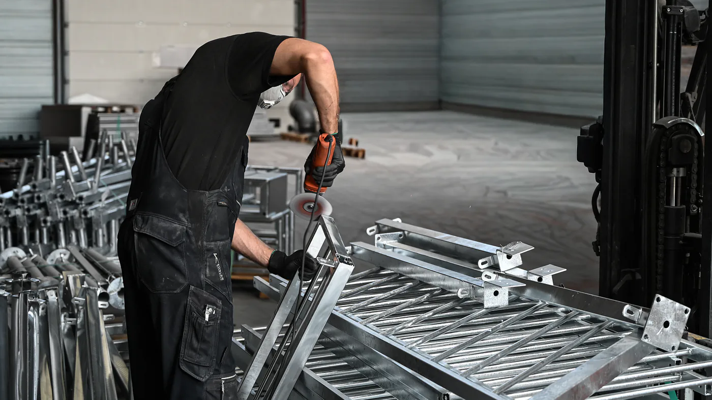 Medewerker van Thermicoat slijpt zinkpunten weg op een verzinkt frame