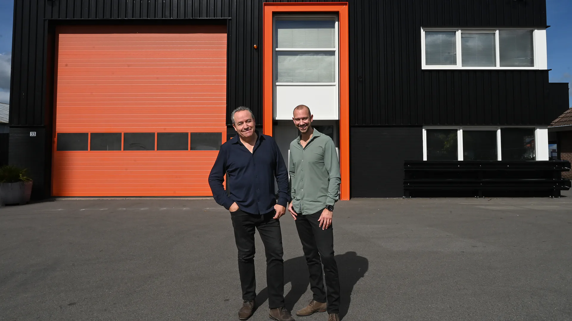 Erwin en Martin, eigenaren van Thermicoat, voor het zwarte bedrijfspand met oranje deur in Brummen
