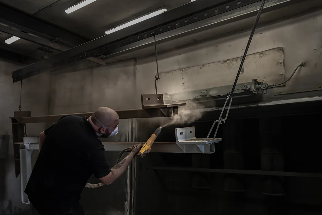 Coater brengt poederlak aan op een ligger in de spuitcabine